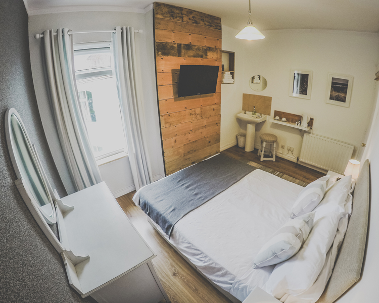 A double room decorated in a maritime style coming along with a TV, sink, hangers and shabby chic furniture