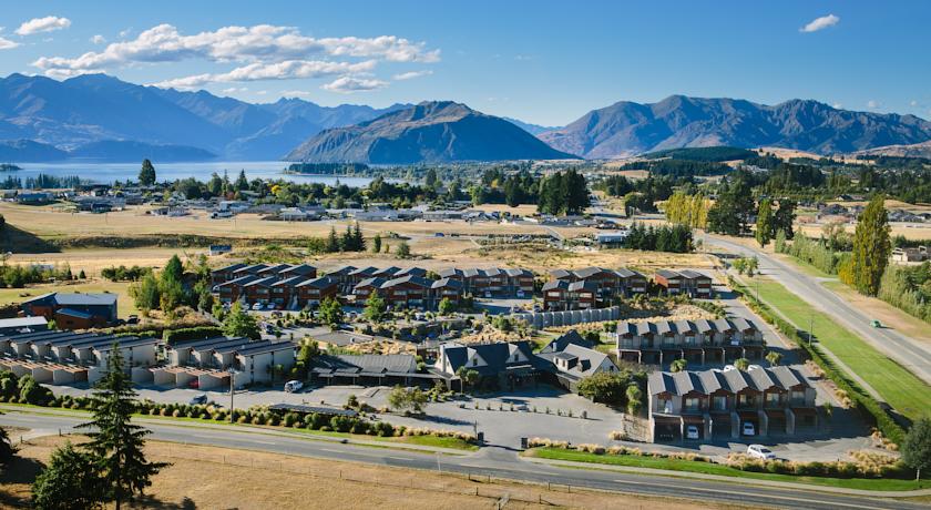 View of Oakridge Resort in Wanaka surrounded by beautiful mountains and lush greenery.