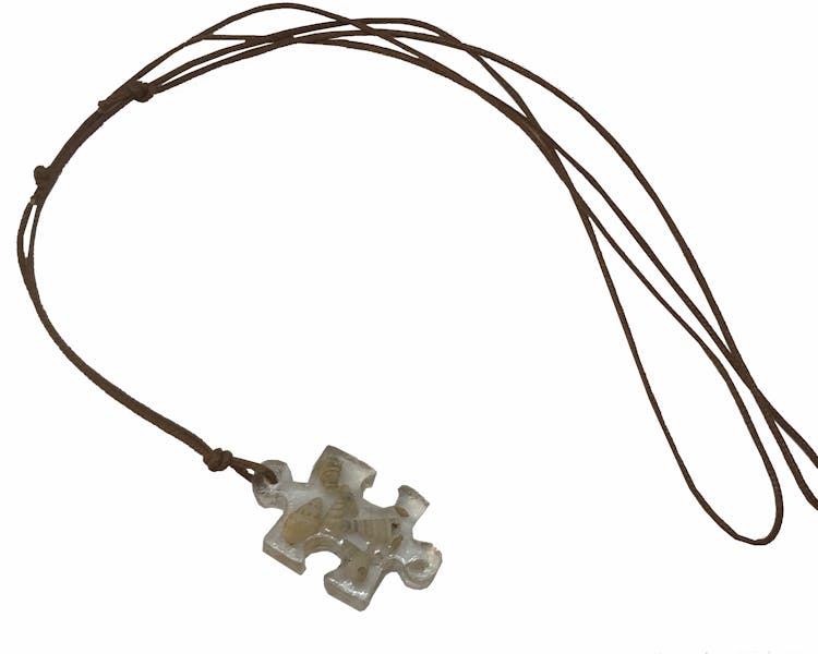 Resin puzzle Piece necklace featuring local miniature shells.
