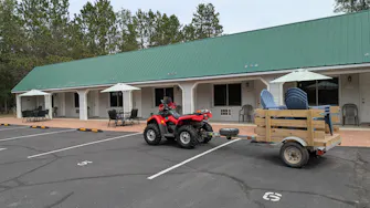 Pictured is a 4 wheeler pulling a trailer filled with chairs. In the background is the motel with the patio furniture.
