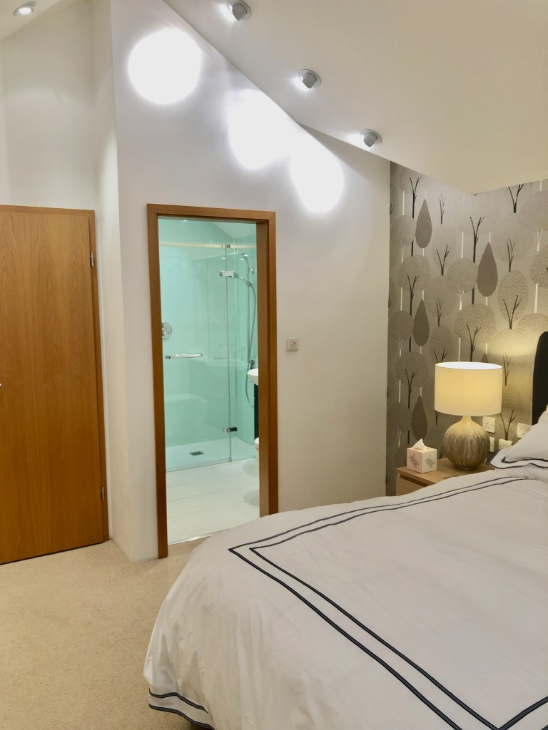 Bedroom 2 view of bedside table lamp and open ensuite door.