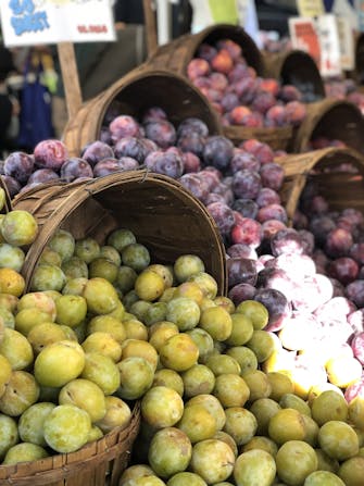 Green and purple plums in baskets