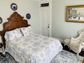 The Creighton Room with blue floral bedding and large victorian mahogany headboard at The Victorian on Main, Fairfield, Il