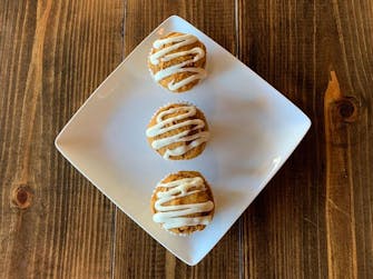 3 muffins on a plate with white drizzle