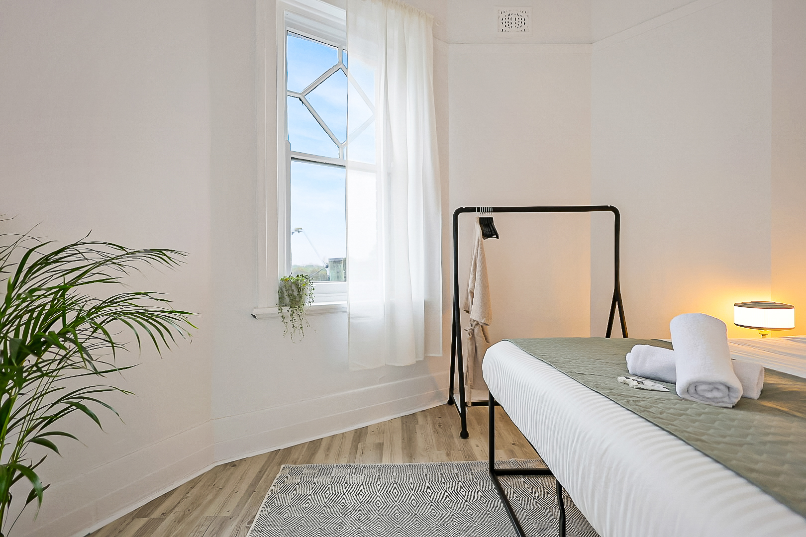 Large queen bed in deluxe double room with clothes rail, complimentary toiletries and towels.