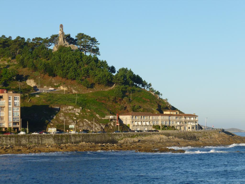 View of the hotel from a boat in the sea, and the Virgin of the Rock at the top