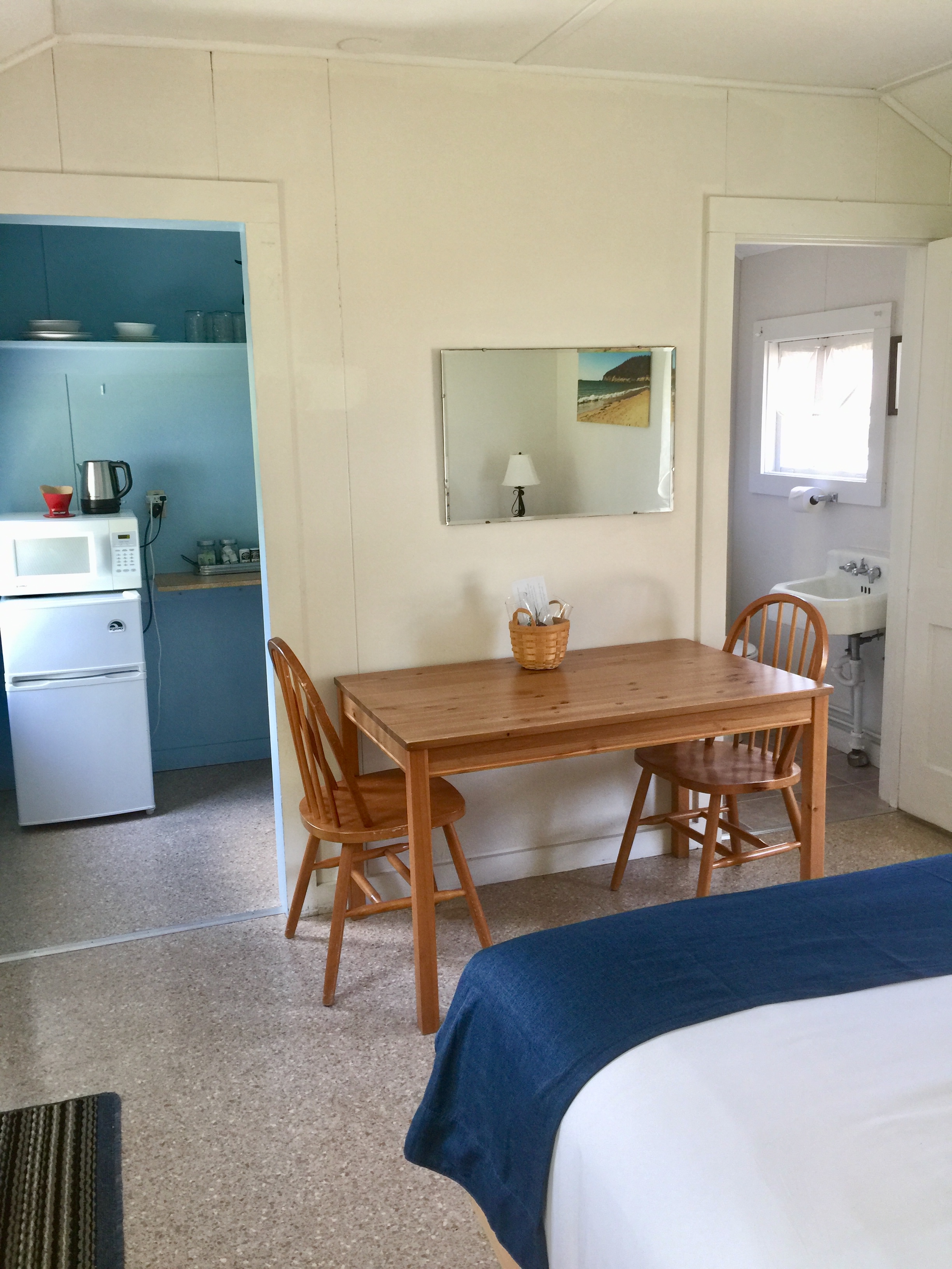 A small hotel room with a kitchenette, dining area, and bathroom.
