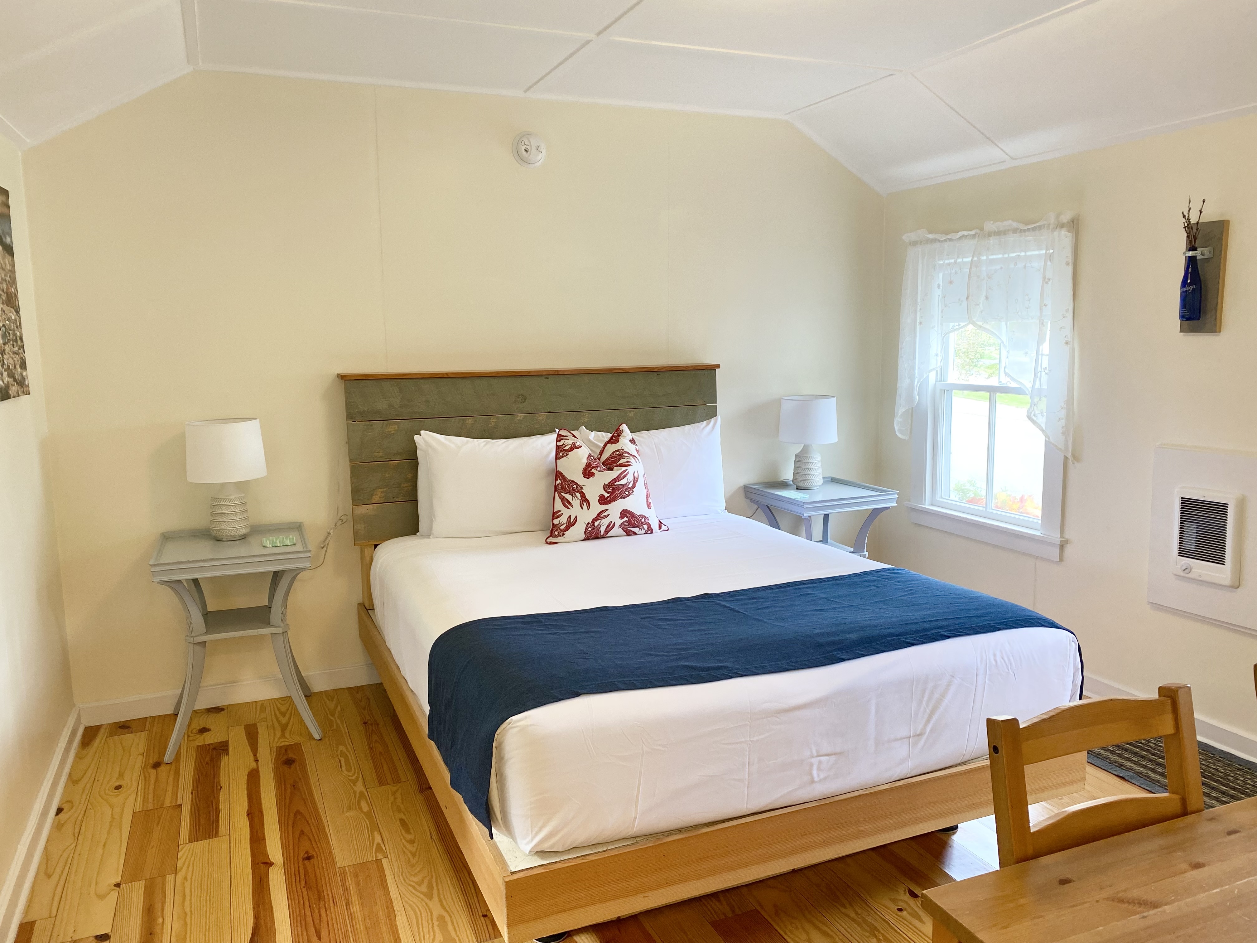 A hotel room with a bed, two nightstands, a lamp, and a window