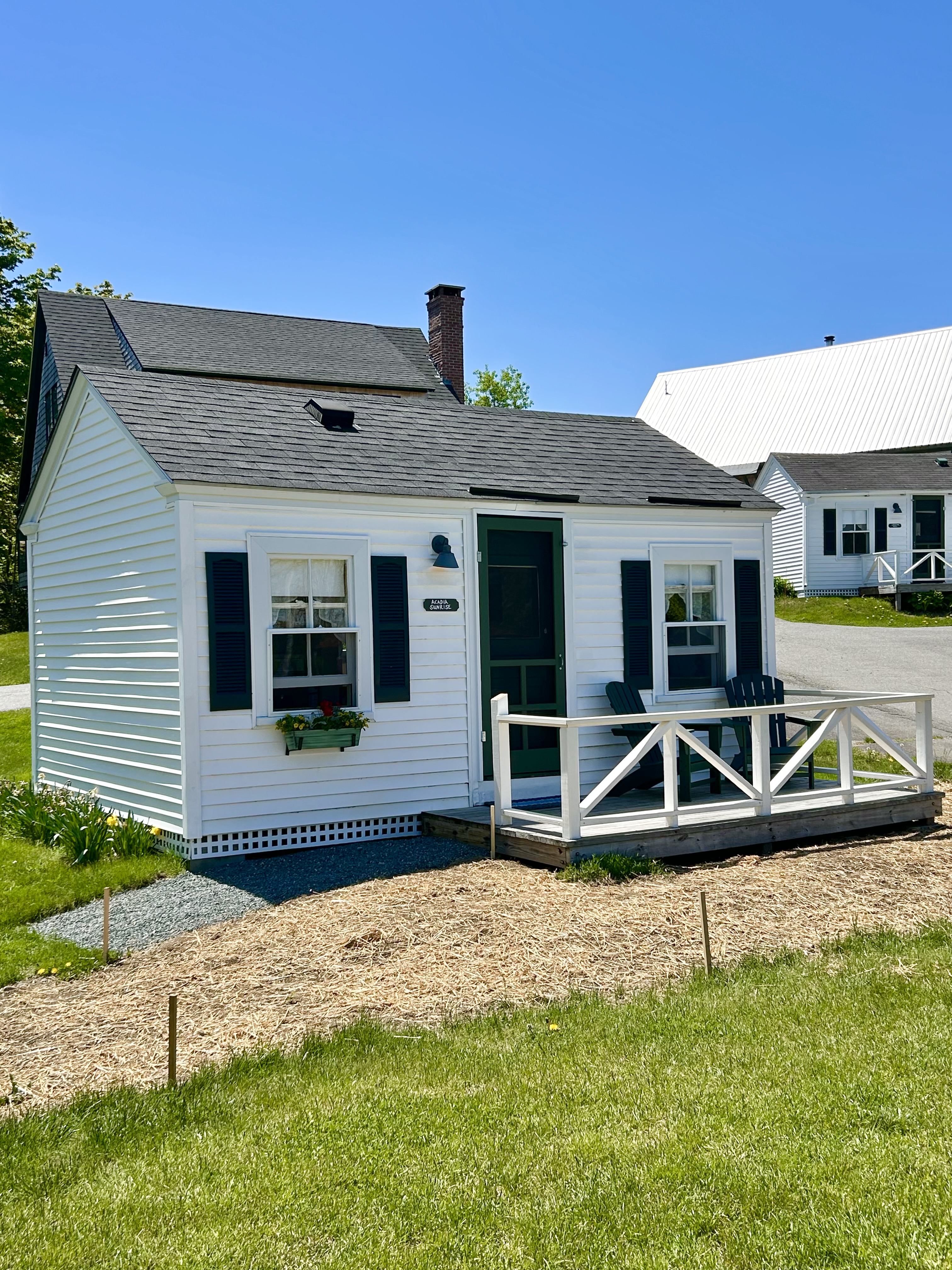 A small white cottage with a green door and a small porch