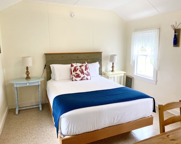 A wide view of a bedroom with a bed, two nightstands, a window, and a chair.