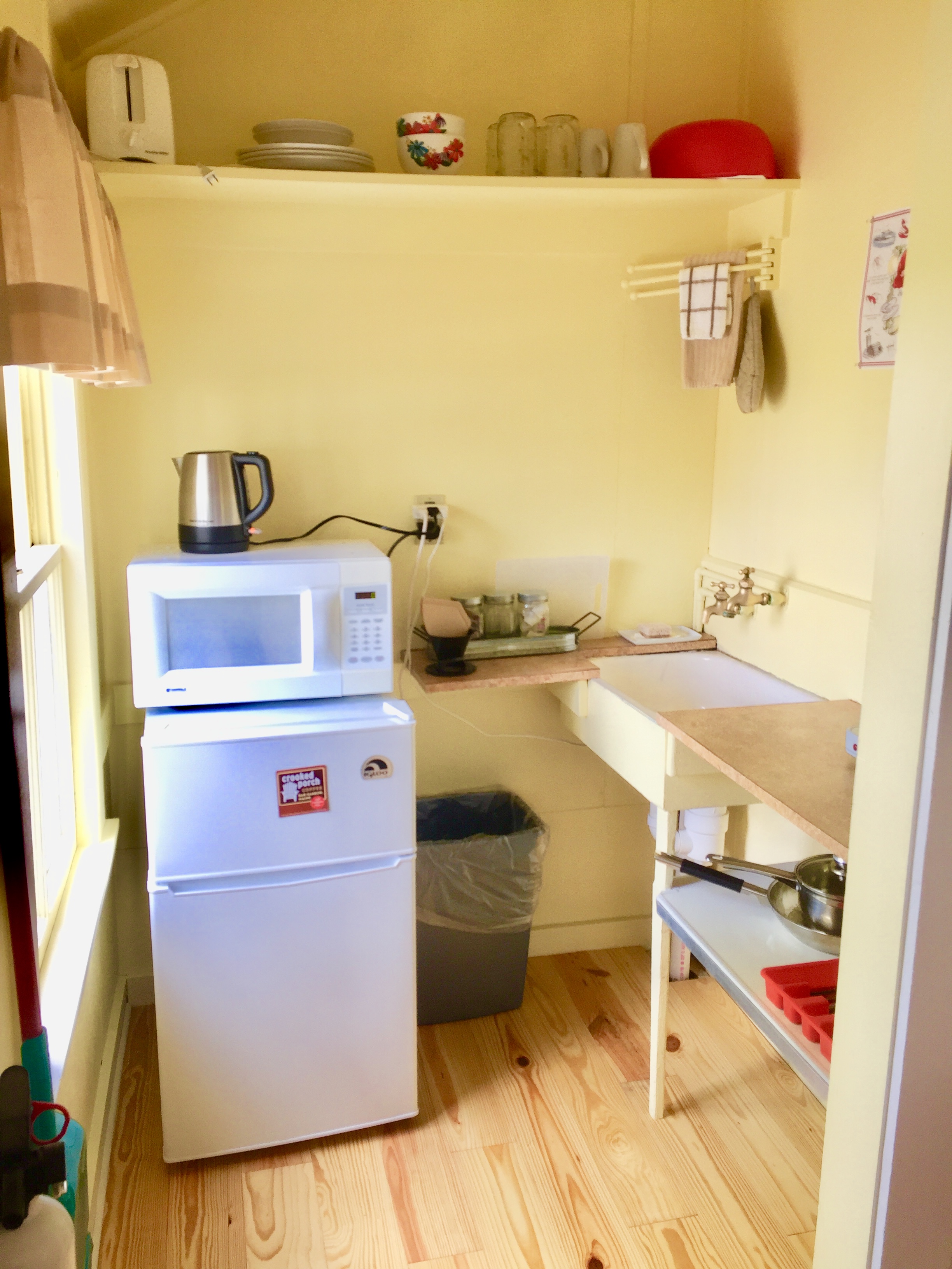 A small kitchenette with a microwave, mini fridge, sink, and countertop.