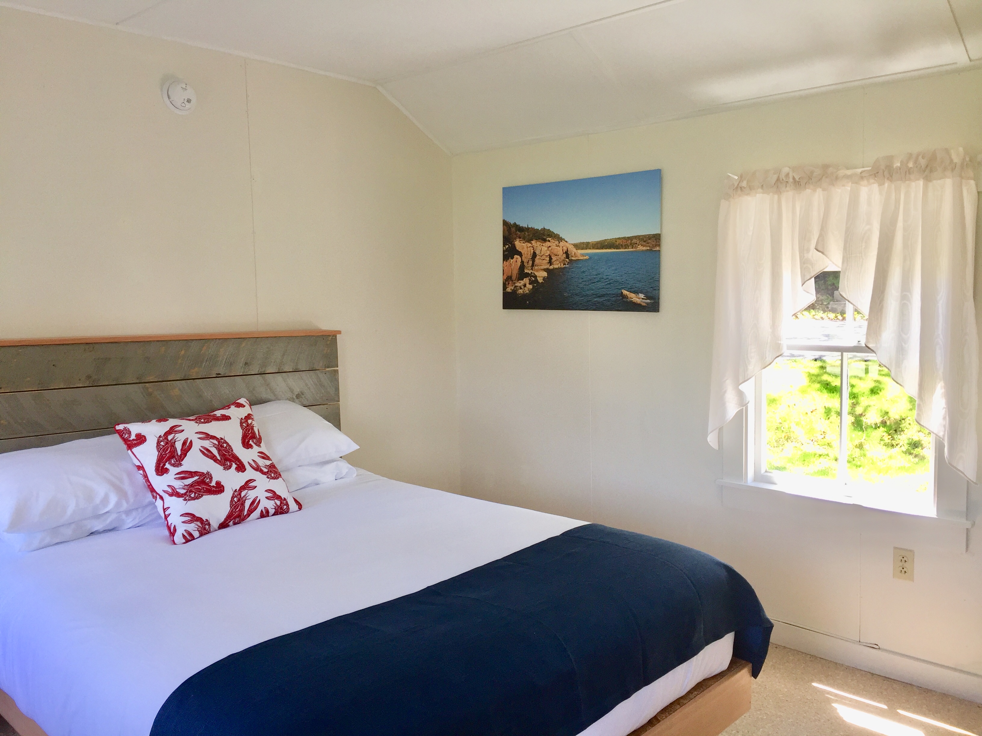 A bedroom with a bed, window, and picture on the wall.