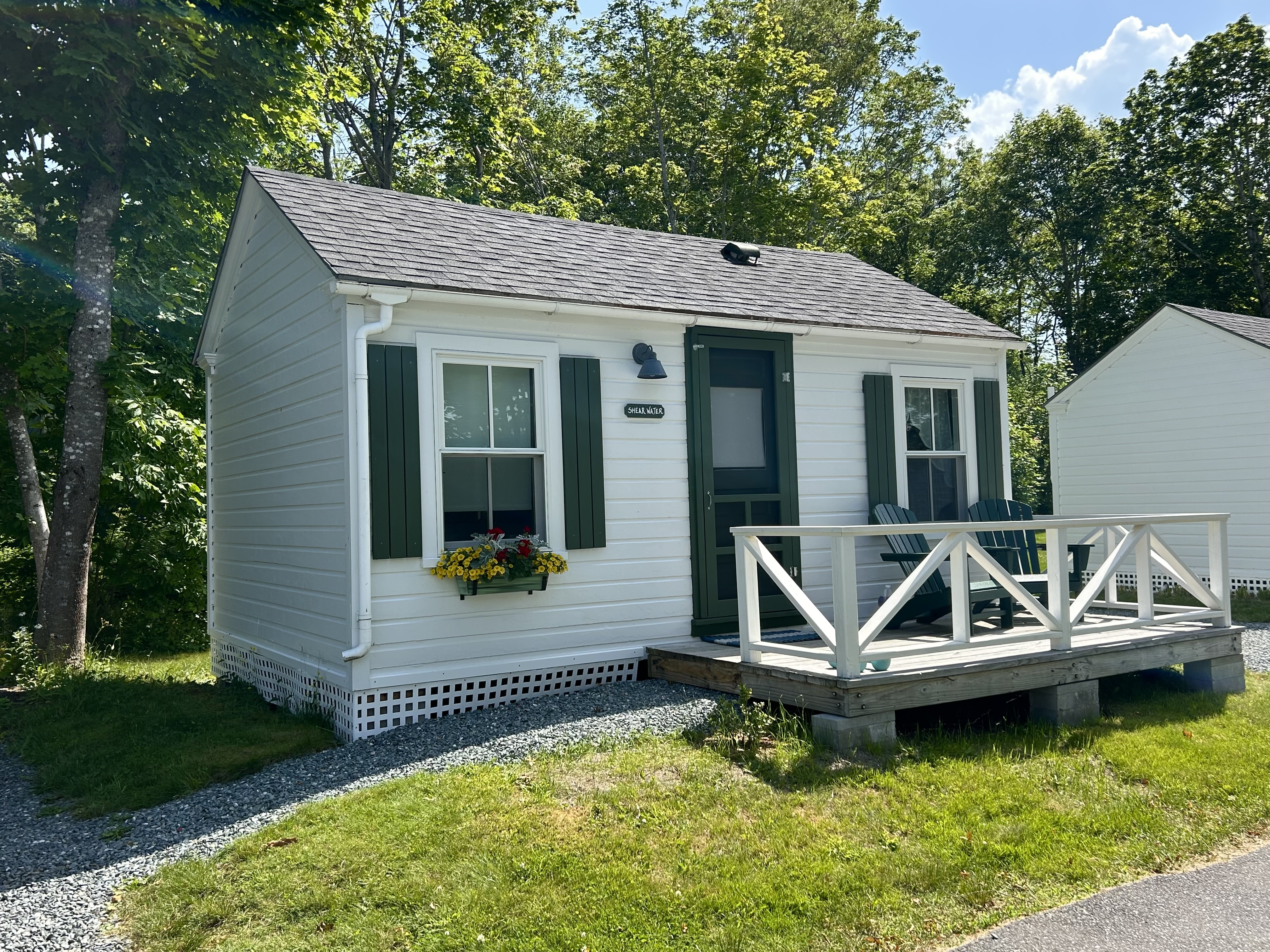 A small white cottage with green trim and a porch