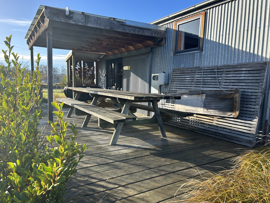 An outdoor eating area beside a rustic cabin at Musterer's Accommodation, Fairlie.