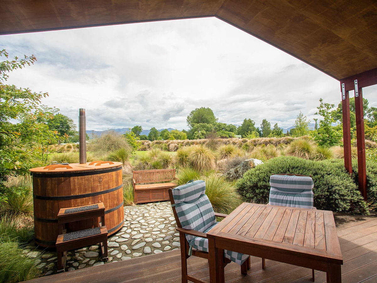 An outdoor eating area and hot tub with native plants at Musterer's Accommodation, Fairlie.