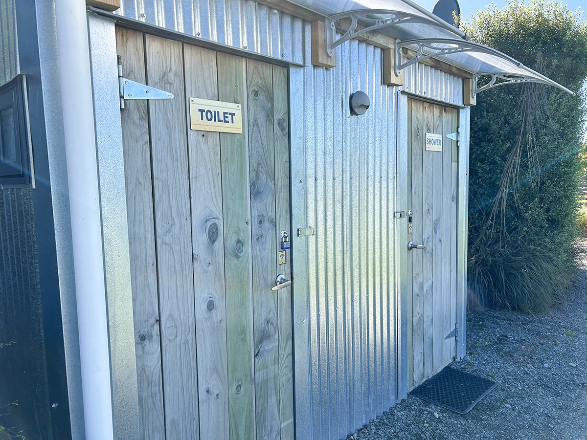 A wood and corrugated iron bathroom block with signage that says Toilet.