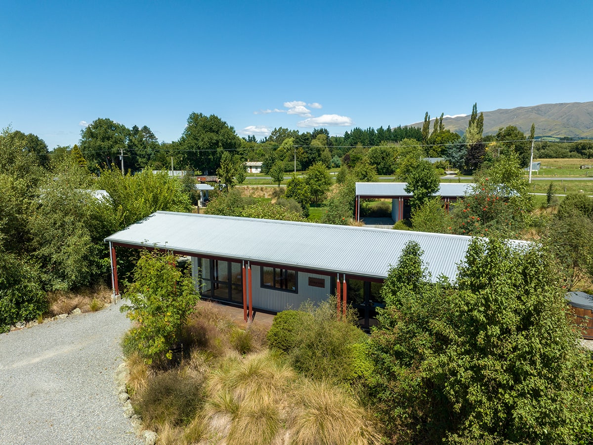 Rustic cabins with native trees and plants at Musterer's Accommodation, Fairlie.