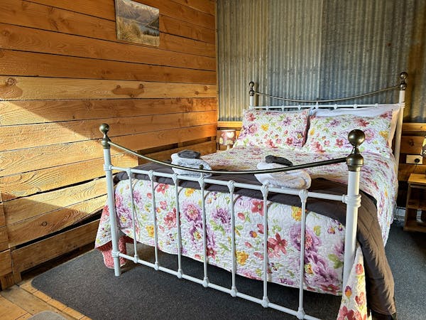 A timber room with large iron-framed bed at Musterer's Accommodation, Fairlie.