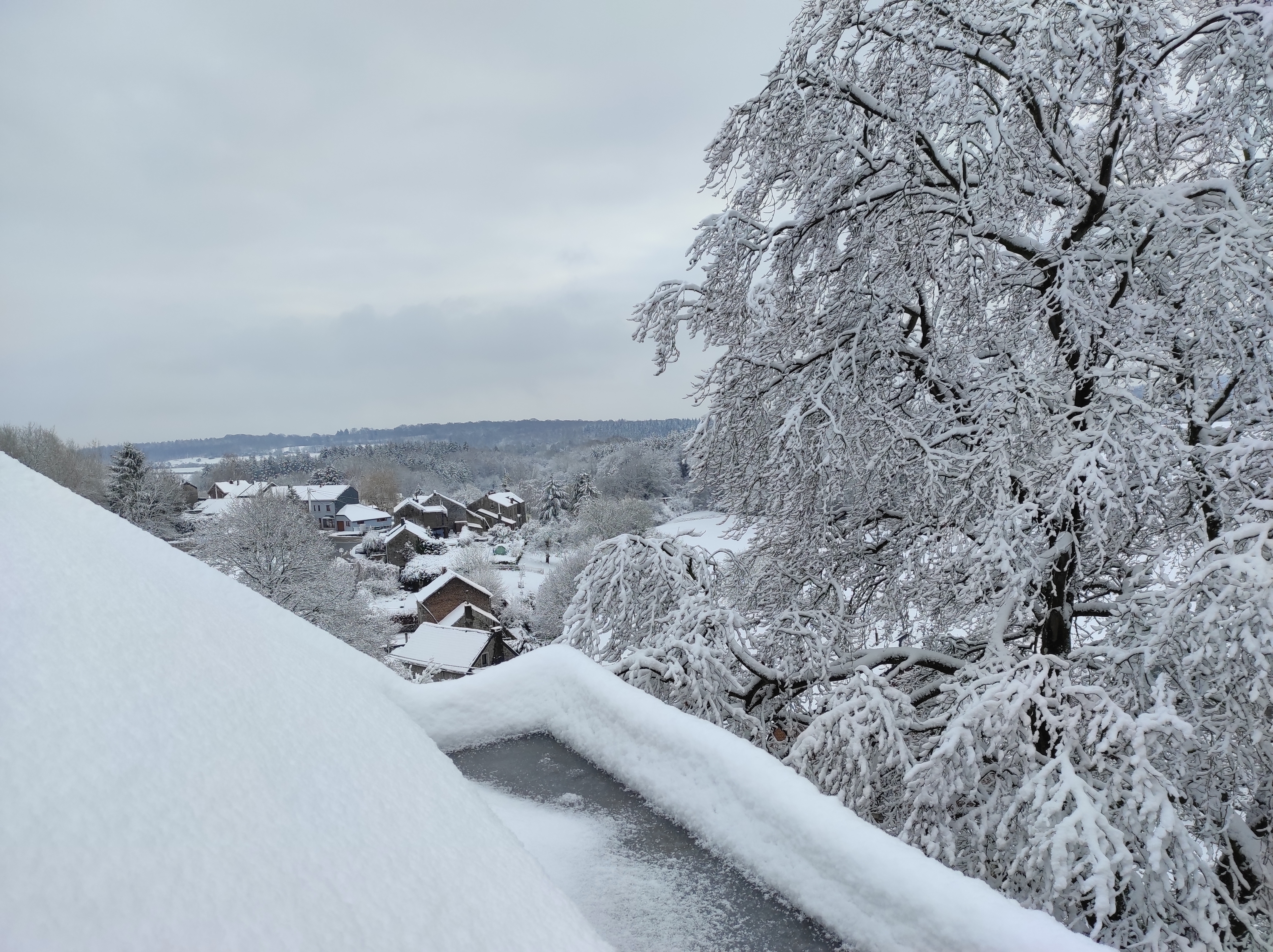 View of the snowy landscape of the Ourthe Valley from the window of a room at La Maison Vienvenue, a cycling accommodation.