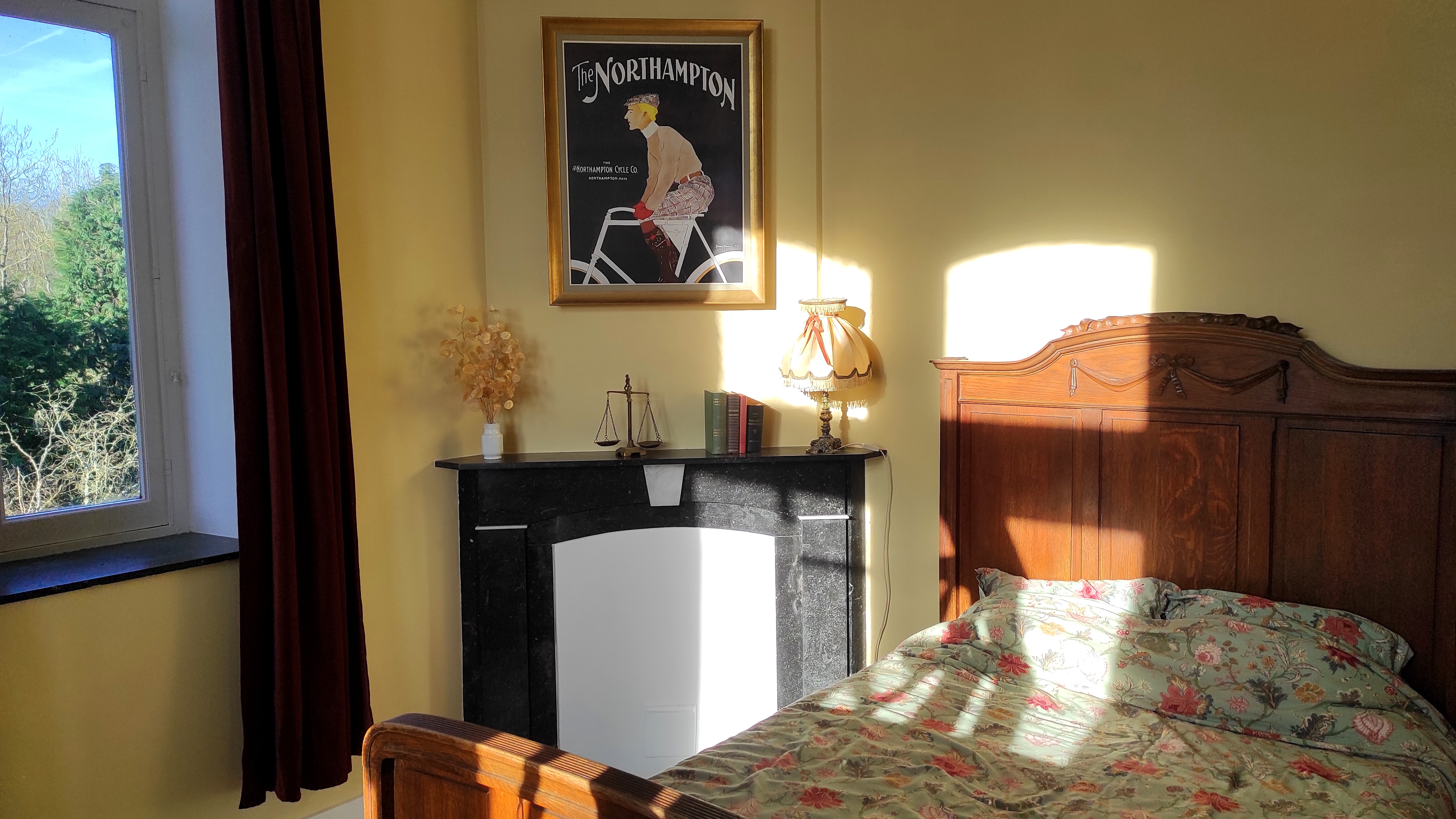 Charming spacious room at La Maison Vienvenue with cycling-themed decoration, featuring Art Nouveau style posters.