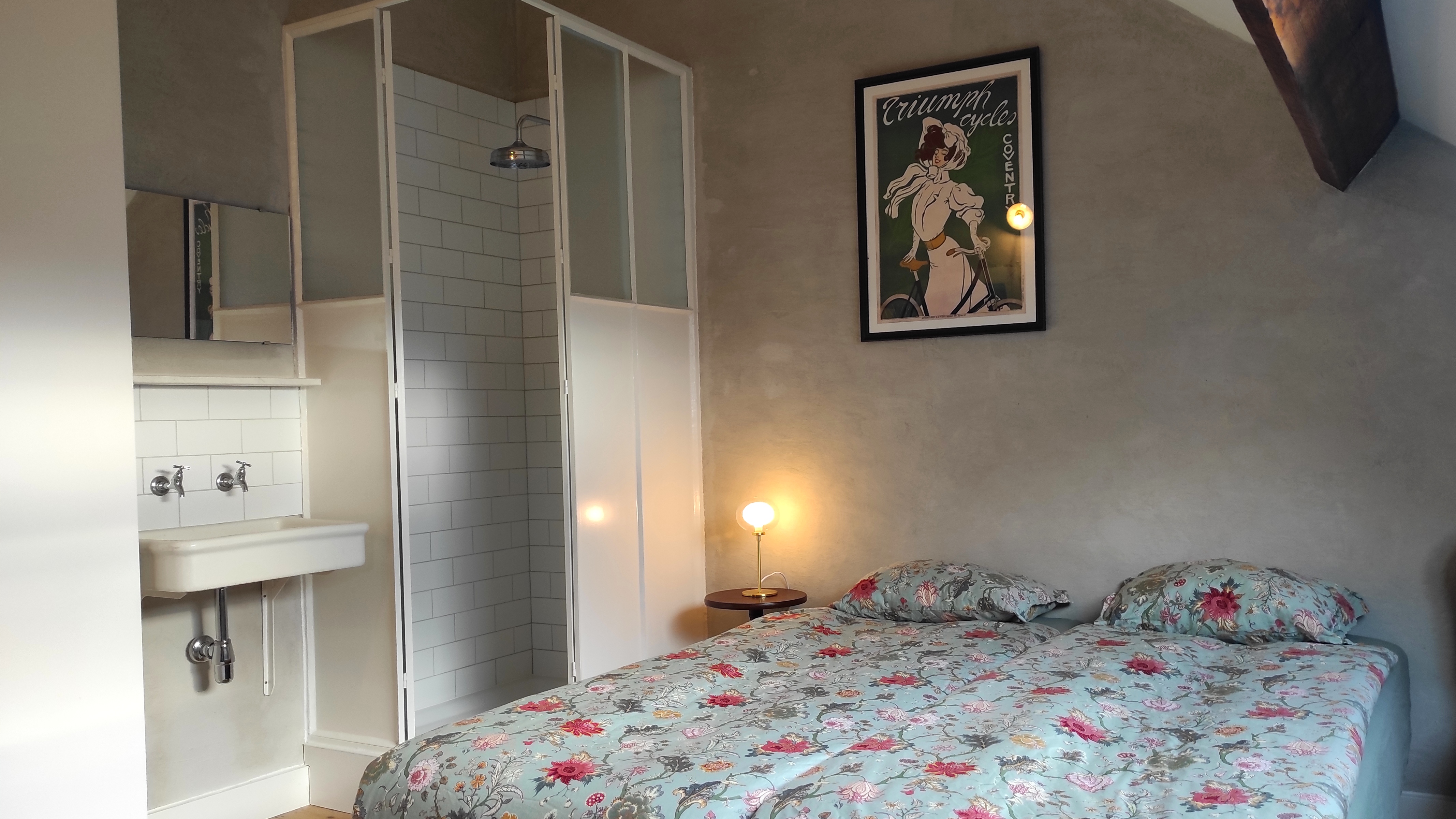 Cozy and charming room at La Maison Vienvenue with its own shower, featuring Art Nouveau style posters and cycling-themed.
