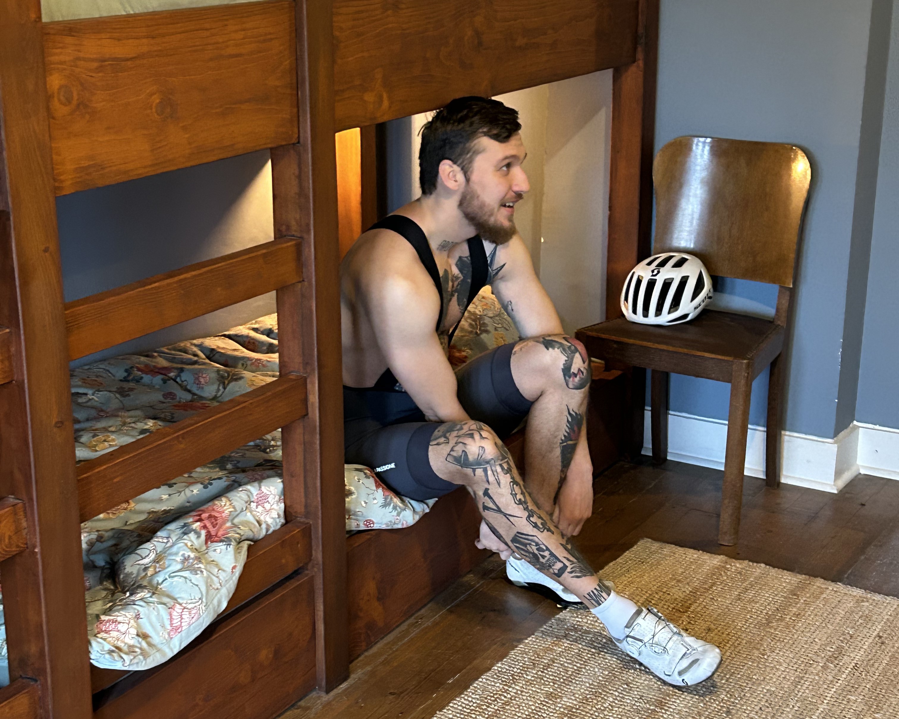 Cyclist in a hostel-like room at La Maison Vienvenue, getting dressed for a nice bike ride while sitting on the bed