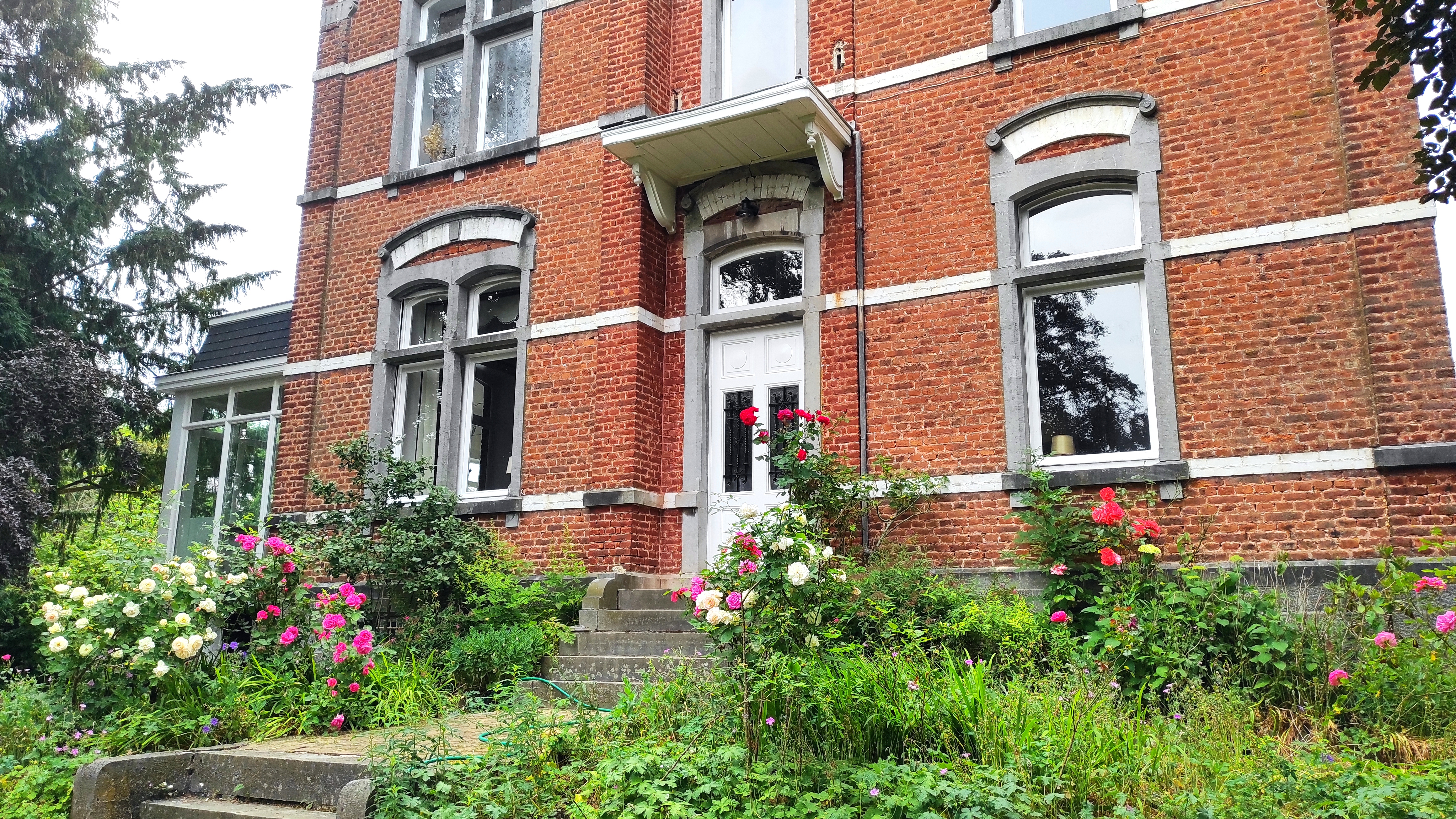 Facade and front garden with flowers of La Maison Vienvenue, a charming accommodation for cyclists in an old manor house.
