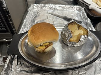 "Grilled cheese burger served with a loaded baked potato."