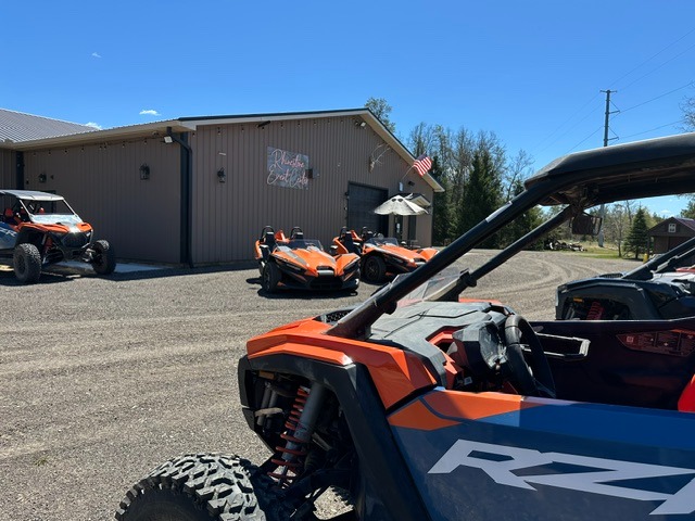 Polaris RZR and Slingshot rentals parked in front of the Rhinestone Event Center at Best Bear Resort in Irons MI