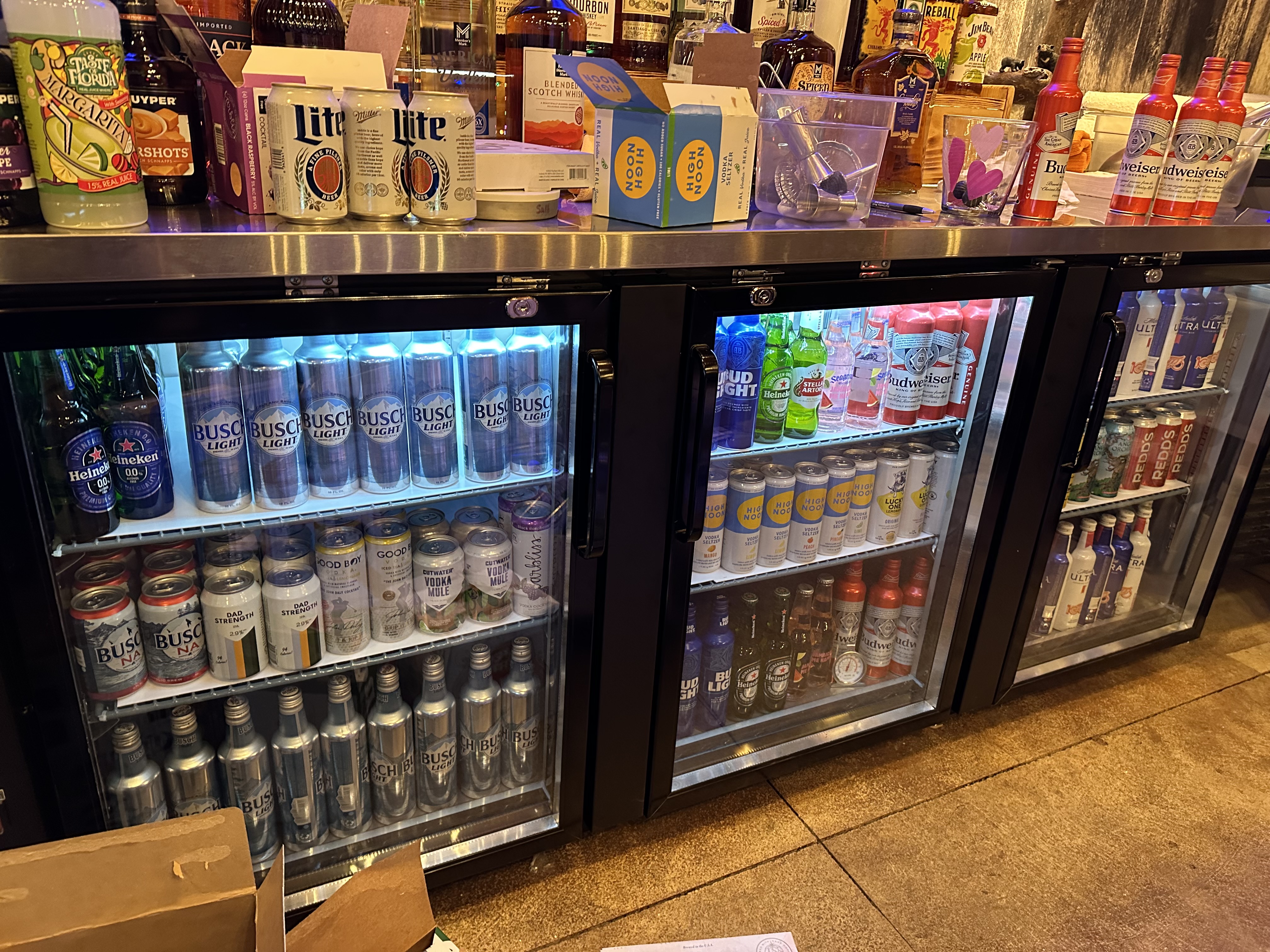 Bar stocked with various spirits, illuminated by a rhinestone 'Bar' sign.