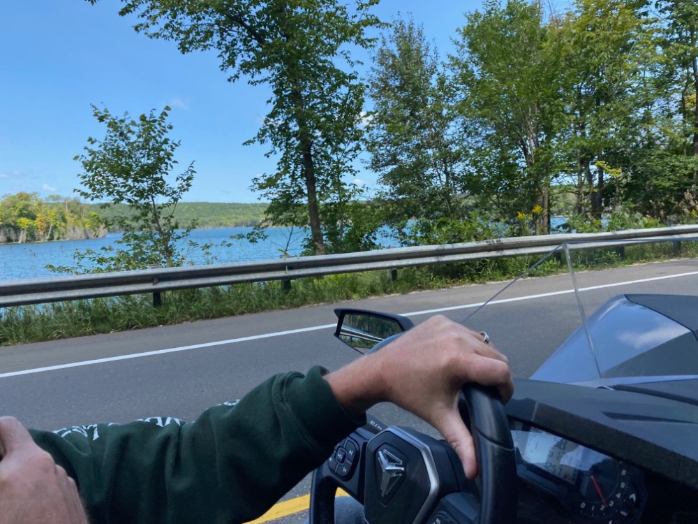 POV driving a Polaris Slingshot past a Michigan lake near Best Bear Resort.