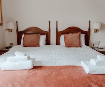 A cosy bed with crisp white sheets and a warm red throw creating a soothing and inviting ambiance.