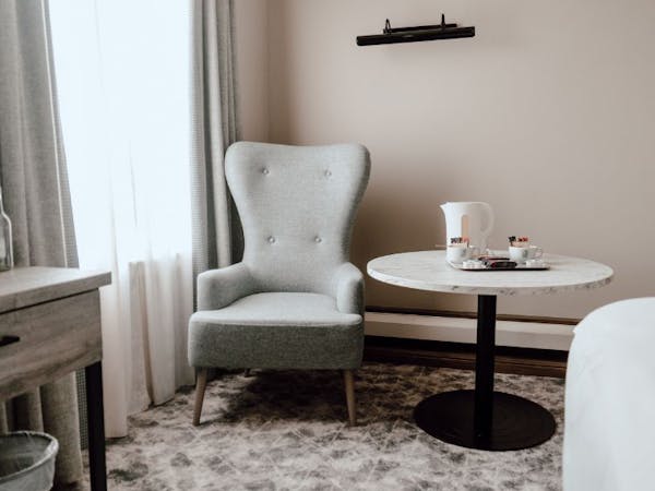 Hotel room setup with a chair and table, providing a comfortable space for guests to unwind or work.