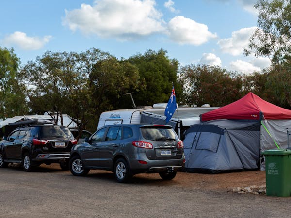 "Powered caravan sites showing caravans and tents with cars parked in front"
