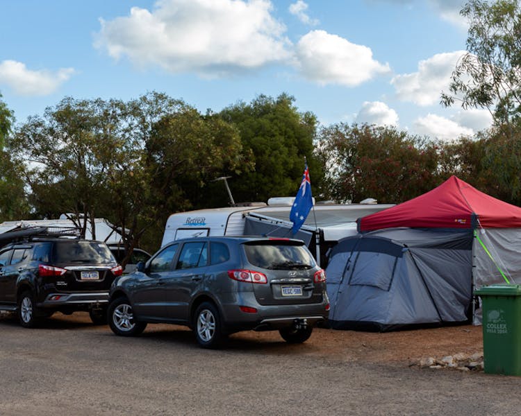 "Powered caravan sites showing caravans and tents with cars parked in front"