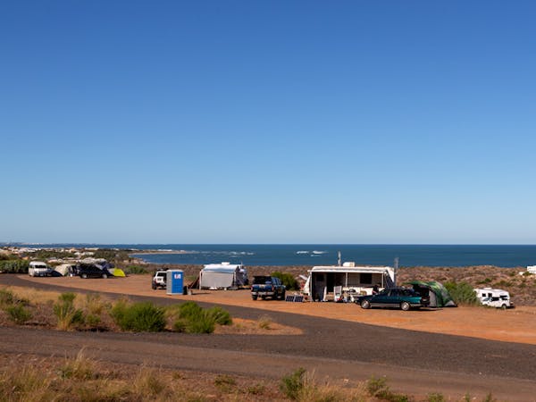 "Un-Powered-camping-with-tents-caravans-in-the-foreground-ocean-and-town-views-in-the-background"