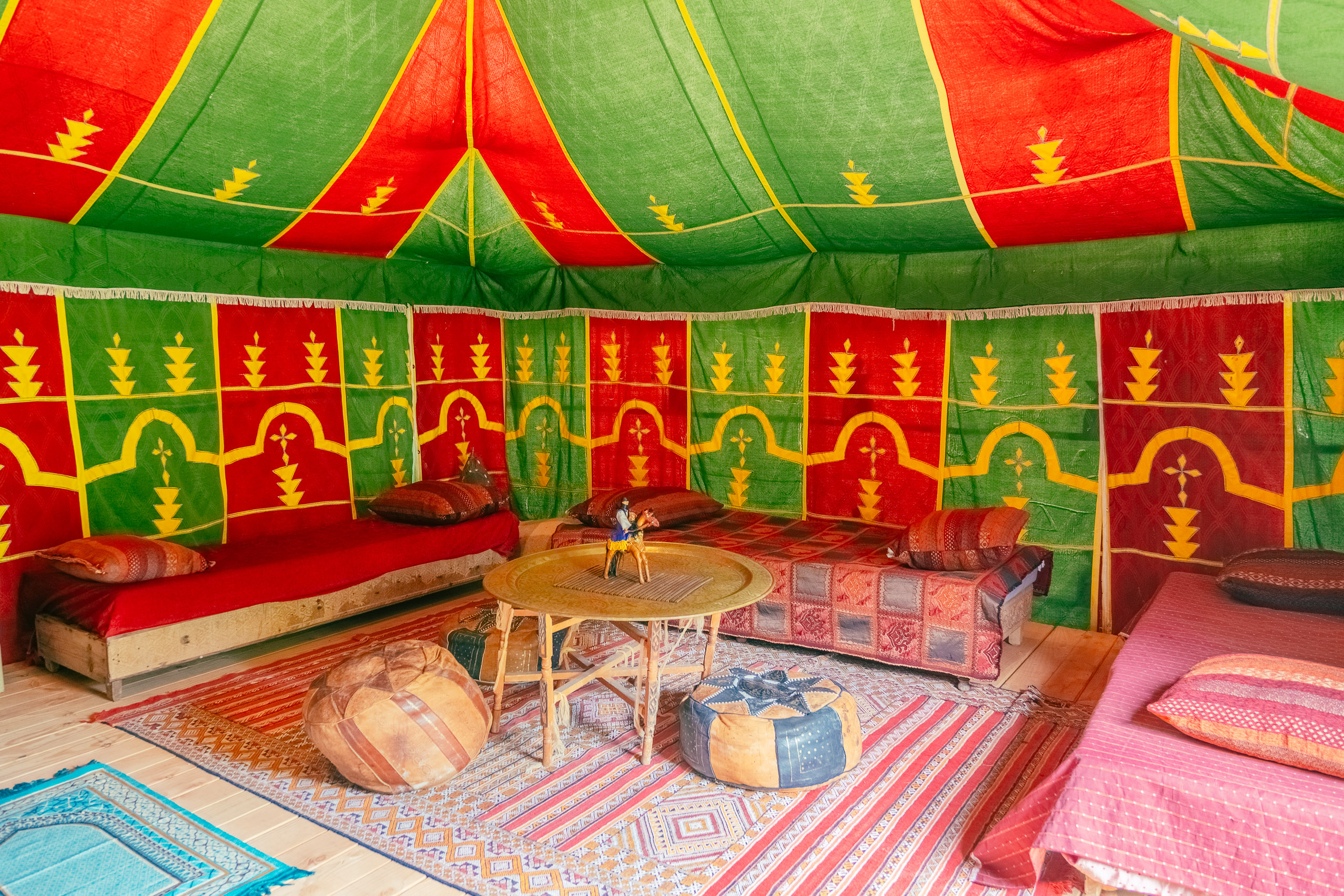 Au-Bonheur-Nomade - vue intérieure de la tente caïdale Marocaine. Plan sur le salon, table, banquette et pouf