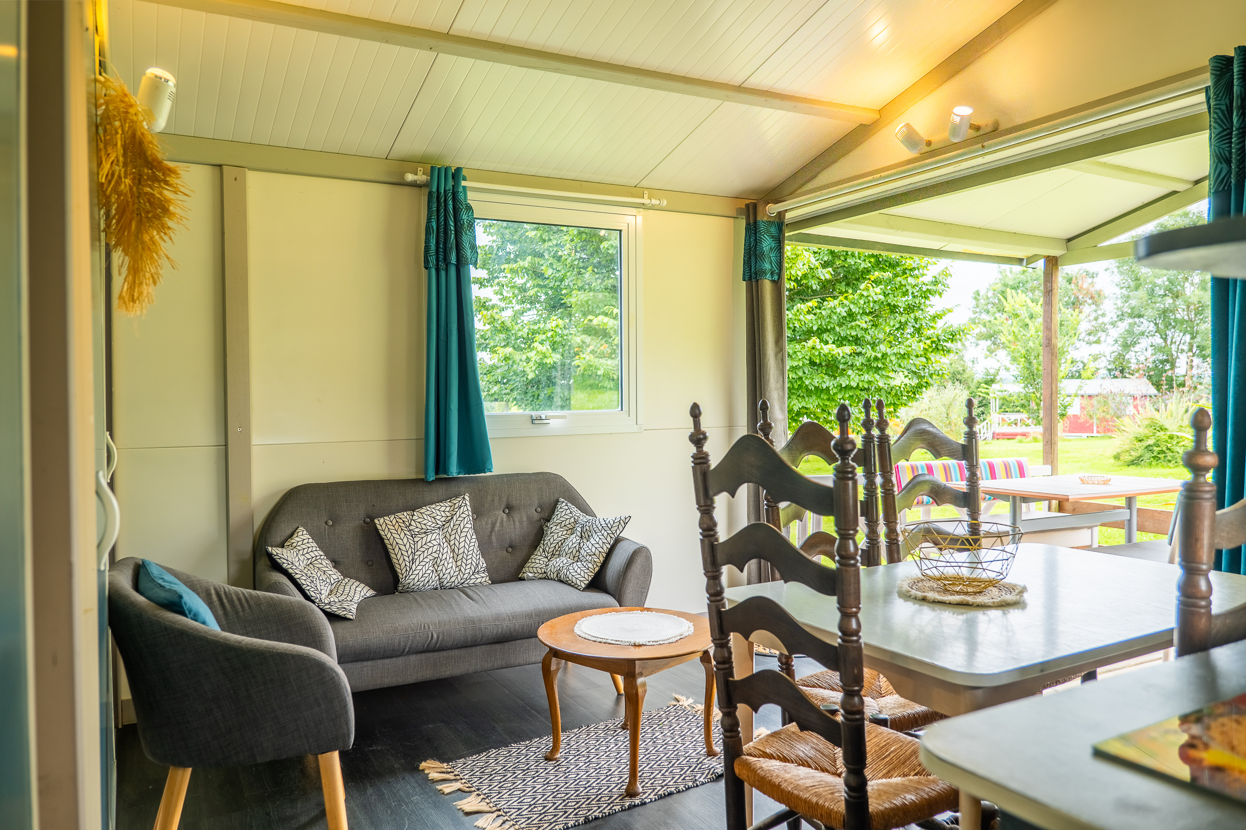 Au-Bonheur-Nomade - vue intérieure du salon et de la salle à manger du chalet marron. Canapé et table basse