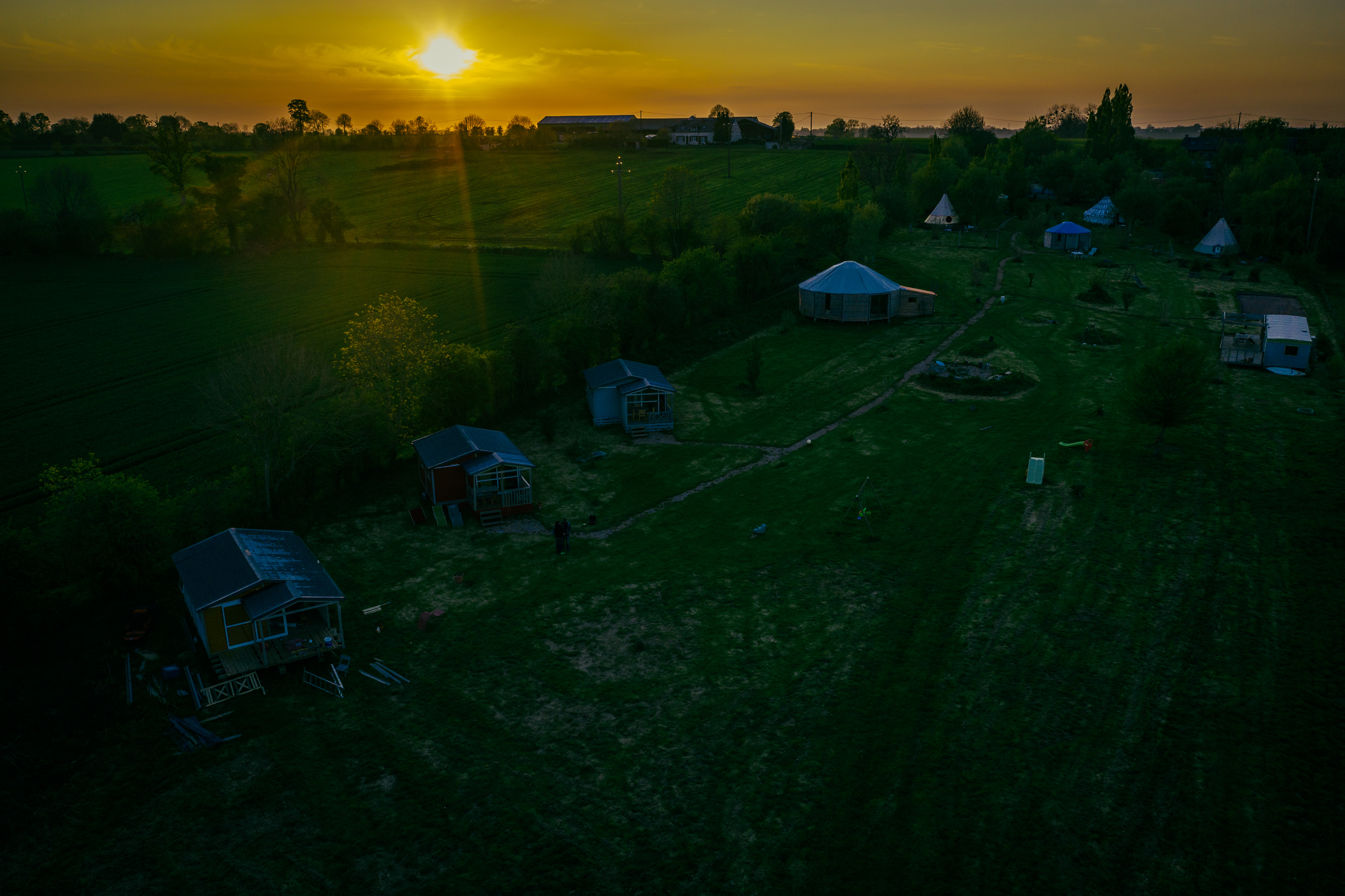 Coucher de soleil sur une partie du domaine en vue aérienne. Chalet en cours de construction.