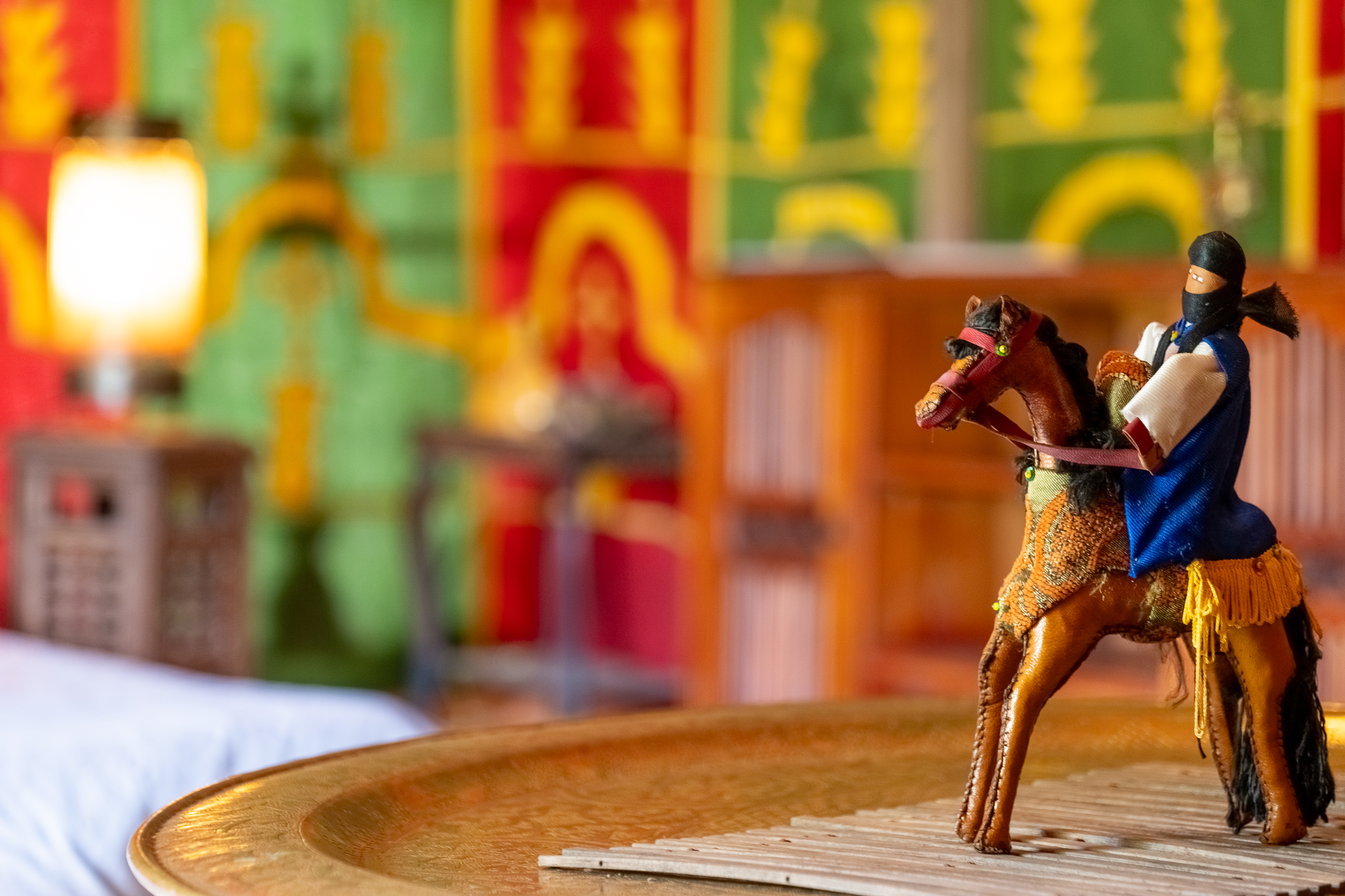 Au-Bonheur-Nomade - vue intérieure de la tente caïdale Marocaine. Plan sur la décoration sur la table, un cheval en bois