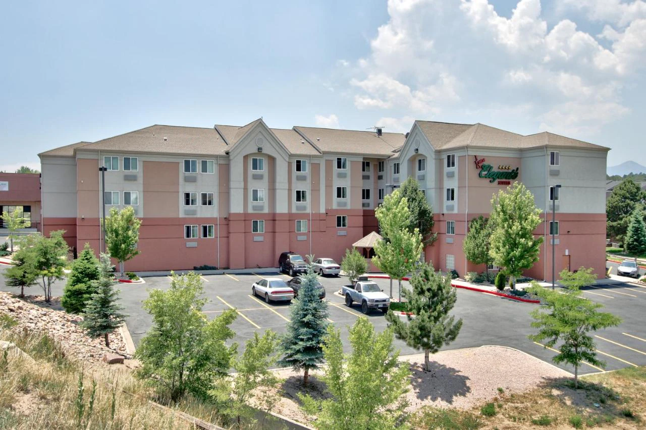 A large hotel building with a parking lot and trees in front