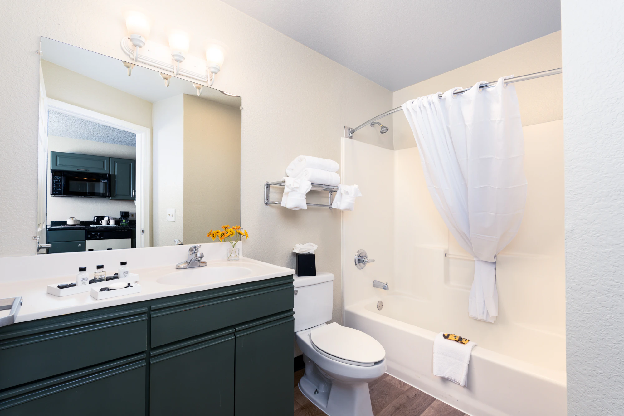 A clean bathroom with a toilet, bathtub with shower curtain, and sink with mirror