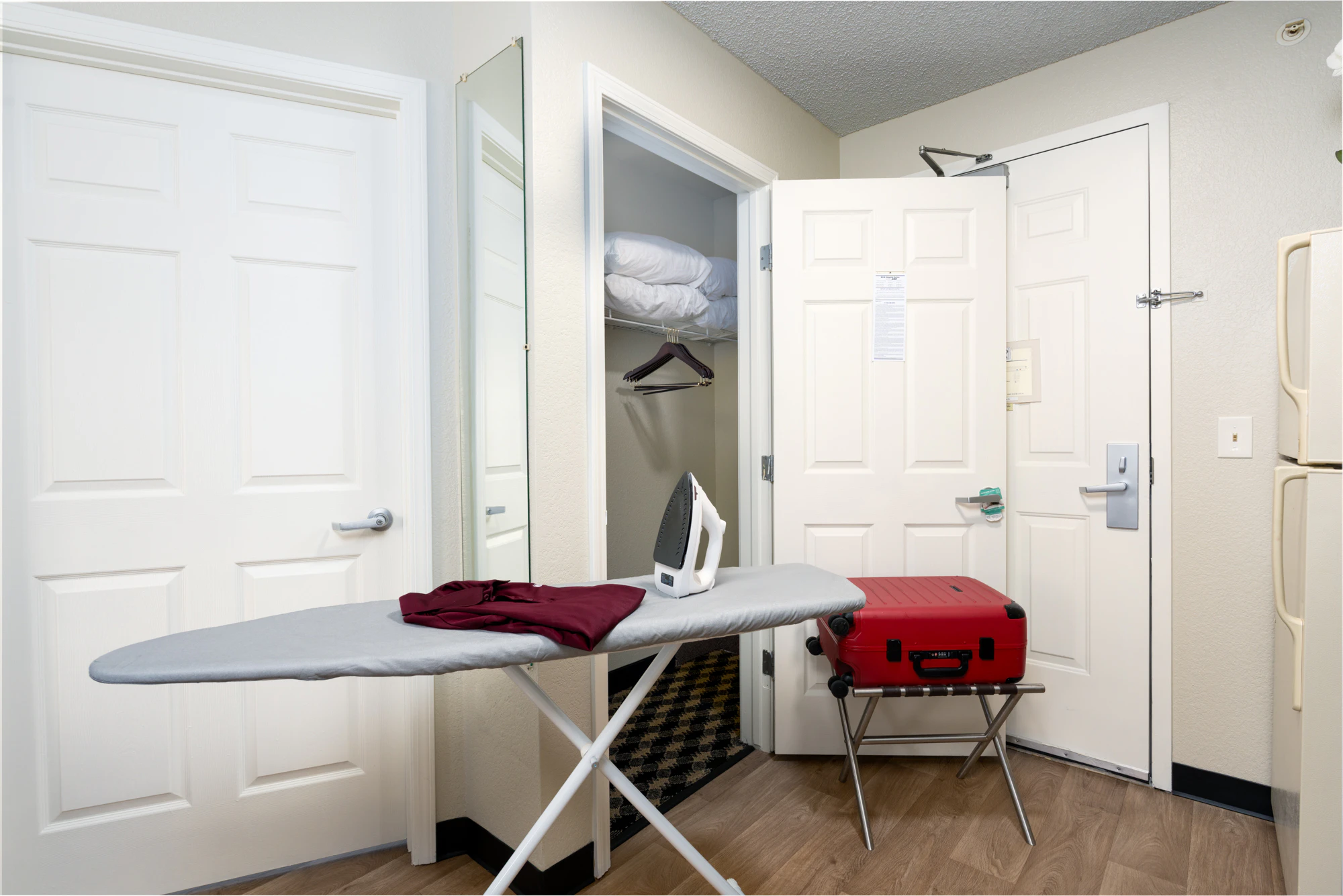 a hotel room with an ironing board and luggage