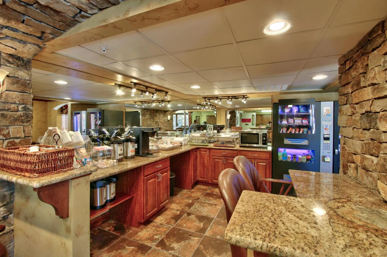 A breakfast buffet area with granite countertops, stone walls, and a snack vending machine.