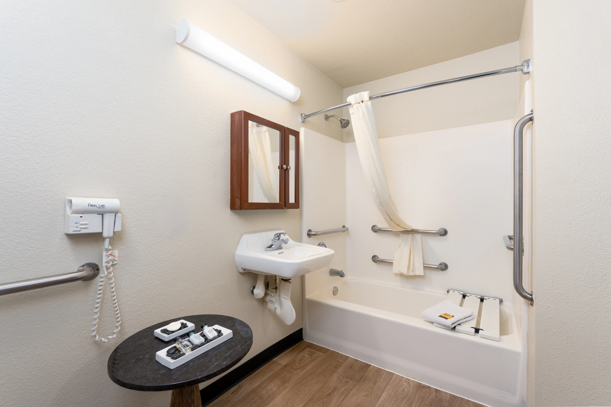 A clean, accessible bathroom with a roll-in shower, grab bars, and a handheld showerhead.
