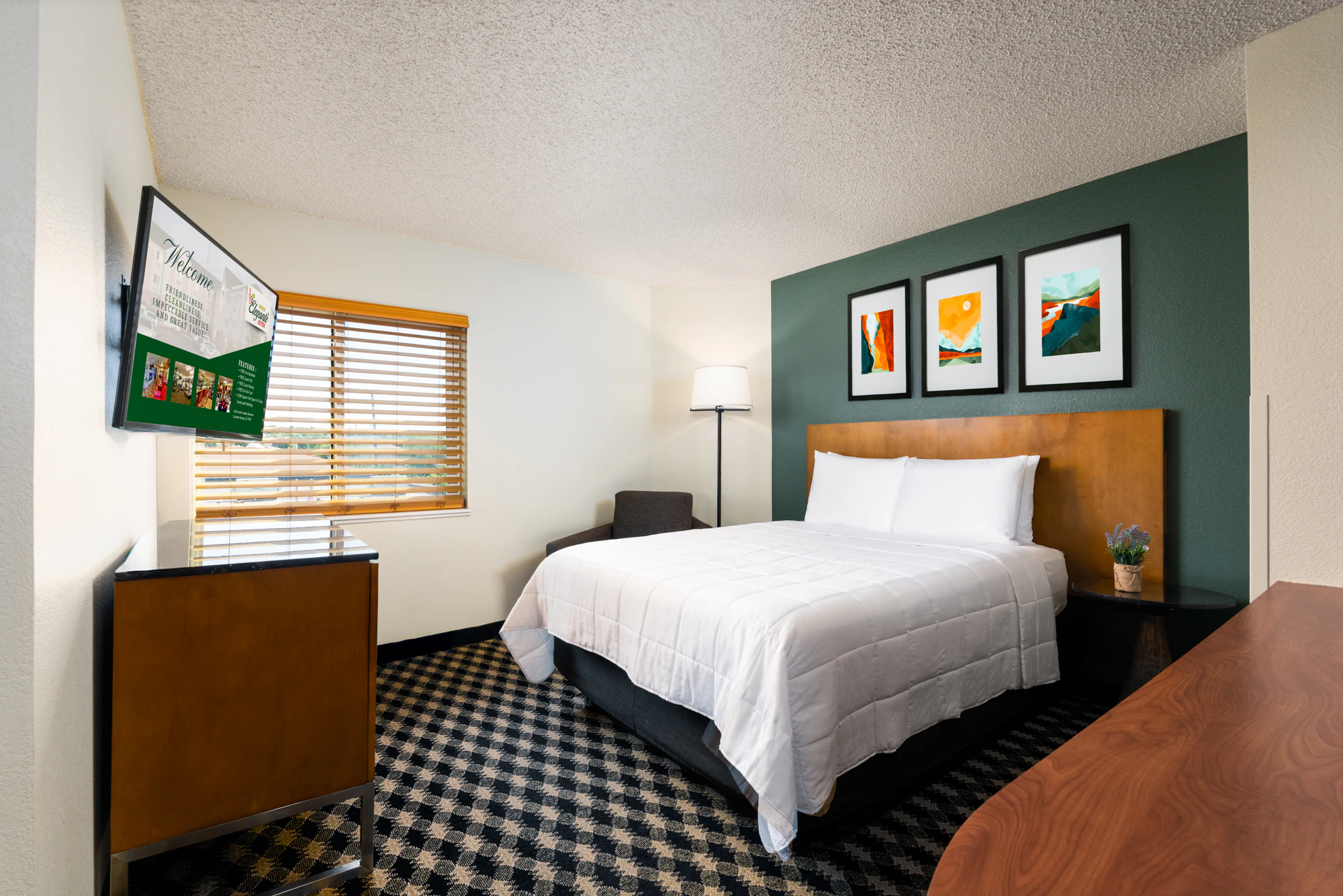 A hotel room with a large bed, TV, and window