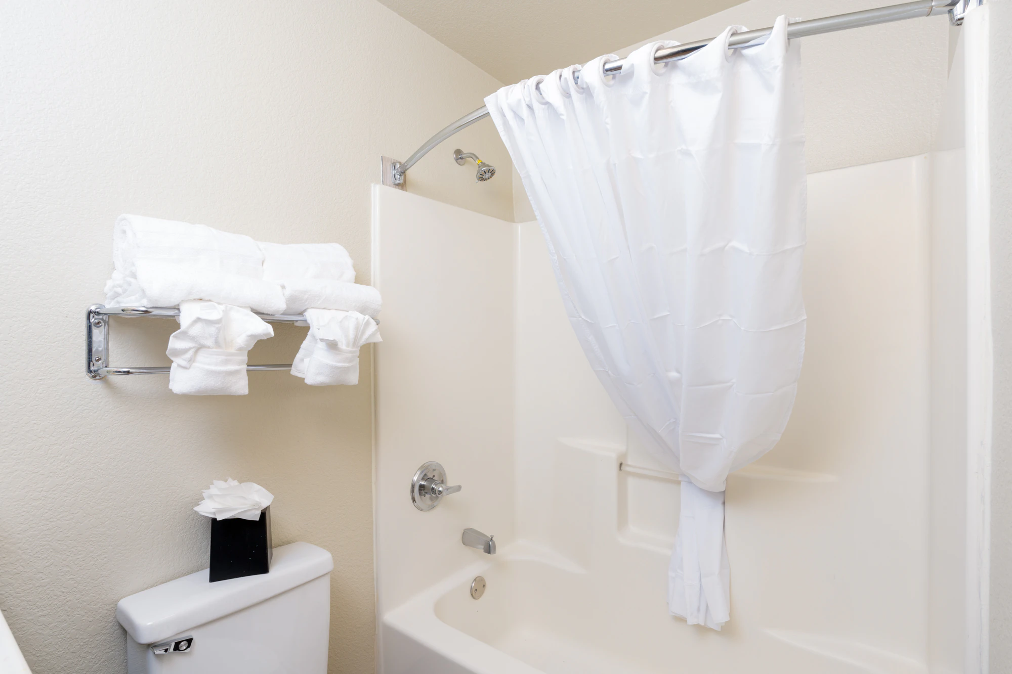 a bathroom with a toilet, bathtub with shower curtain, and towels