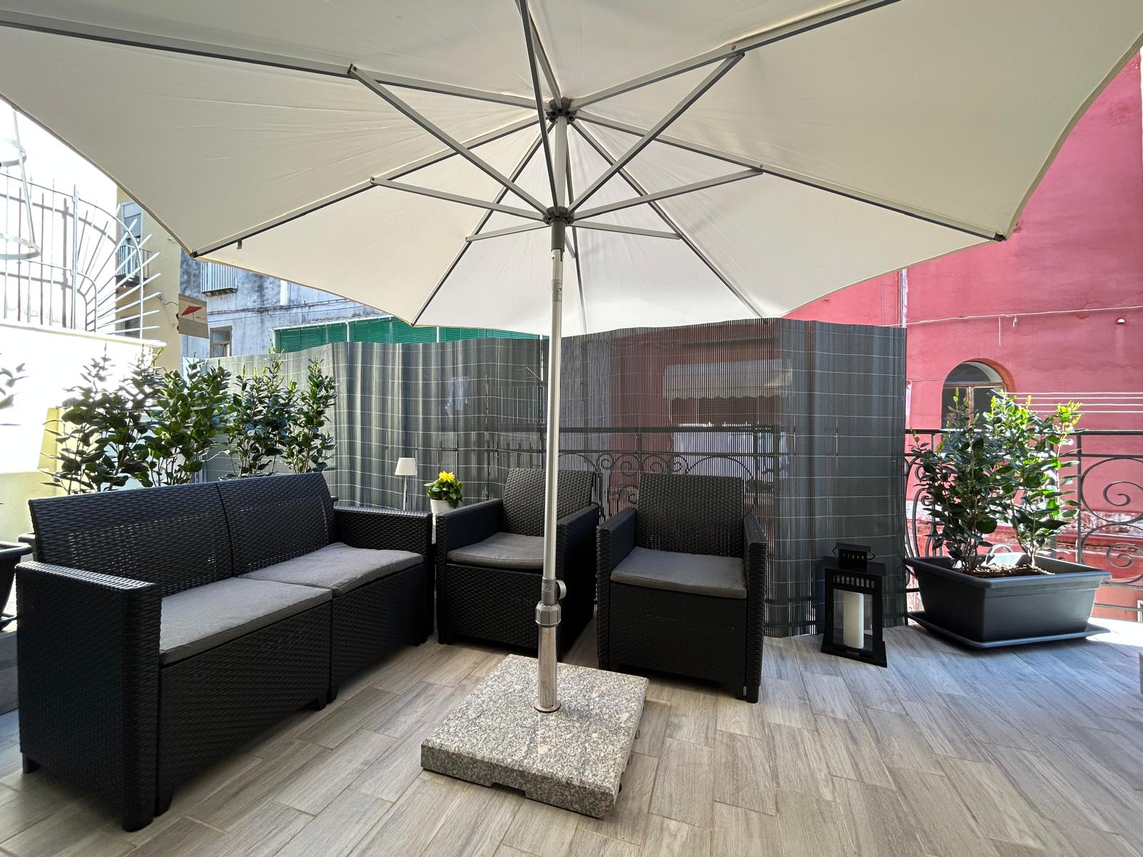 Terrazza esterna arredata con divanetti e ombrellone.