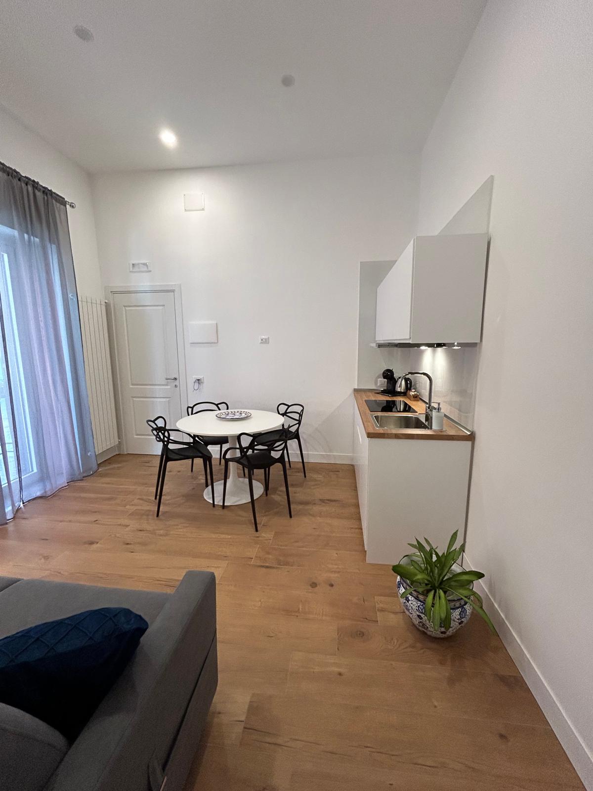 Soggiorno con angolo cottura completo e zona pranzo.