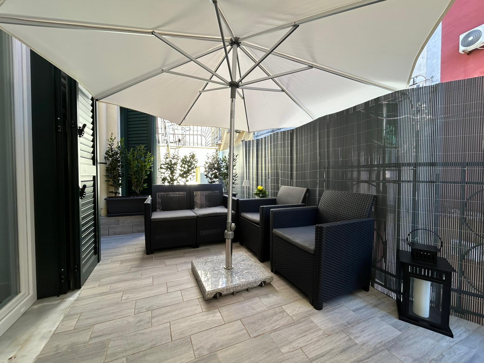 Terrazza esterna arredata con divanetti e ombrellone.